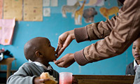 Teacher feeding a child in a classroom